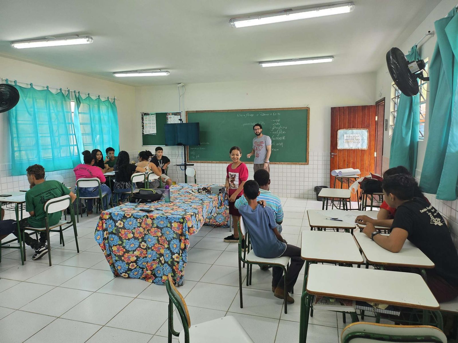 Sala de aula com estudantes em grupos e um educador no quadro, na comunidade quilombola de João Surá